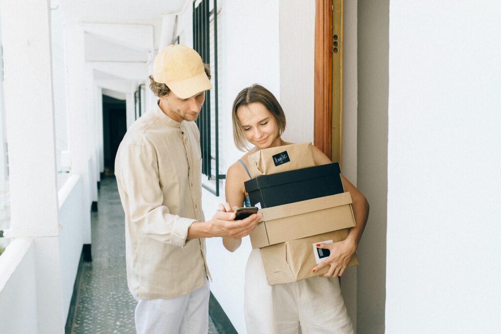 pexels-photo-8939564-8939564 A man and woman engaged in a home delivery package exchange, smiling.